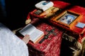 Hand of priest holds opened Holy Bible on the lectern near cross and icons