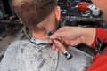 The hand of a professional barber in the process of cutting the back of the head of a client of a young, guy in a salon or