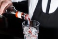 The hand of a professional bartender pours red syrup into a glass of ice cubes. The process of preparing an alcoholic cocktail Royalty Free Stock Photo