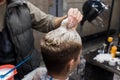 The hand of a professional hairdresser in the process of dyeing the hair of a client in a barbershop or hairdresser
