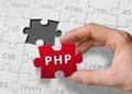 Hand of programmer holds puzzle with PHP programming language