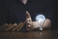 Hand protecting lightbulb with glowing virtual brain from falling wooden block , It is symbol of protect copyright and patent Royalty Free Stock Photo