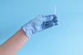 Hand in protective blue gloves hold medicine bottle of vaccine on blue background. Concept of vaccination and healthcare Royalty Free Stock Photo