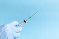 Hand in protective blue gloves hold medicine syringe with vaccine on blue background. Concept of vaccination and healthcare Royalty Free Stock Photo