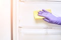Hand in protective glove cleaning fridge. White kitchen furniture Royalty Free Stock Photo