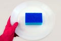 Hand in protective glove holds plate with blue cleaning sponge mock-up Royalty Free Stock Photo