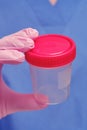 Hand in a protective glove with a jar for testing for the flu virus. The doctor`s hand holds a container for taking samples of