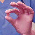 Hand in a protective glove with medicine for the flu virus. Doctor`s hand with one pink coronavirus pill, close-up Royalty Free Stock Photo