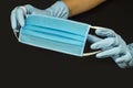 A hand in a protective glove presents a typical surgical mask. Protection against coronavirus