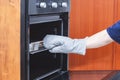 A hand in a protective glove pulls out a cooked hot meat dish from the oven. Safety concept. Kitchen, food preparation Royalty Free Stock Photo