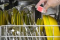 Hand in protective glove, puts the cleaning capsule in the dishwasher, after loading items Royalty Free Stock Photo