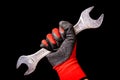 Hand with protective gloves holding wrench tool isolated on black background Royalty Free Stock Photo