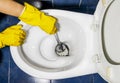 Hand in protective yellow gloves wash toilet in the toilet