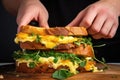 hand pulling apart a cheesy omelette sandwich demonstrating the melted cheese