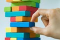 Hand pulling colorful wooden block from the tower in as Risk or Royalty Free Stock Photo