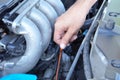 Hand pulling dipstick checking car engine oil