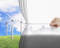 hand pulling gray cityscape curtain revealing group of wind turbines