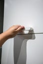 Hand pulling a handle of white upper drawer.