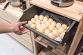 Hand pulling metal kitchen drawer filled with fake eggs for display.