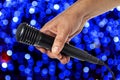 Hand pulls a black microphone on a multi-colored background. Close-up Royalty Free Stock Photo