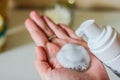 Face cleanser on female hand and cosmetics foam pump container. White blurred background. Royalty Free Stock Photo