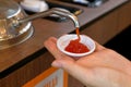 Hand pumping ketchup from sauce pump in to small plastic bowl in fast food restaurant