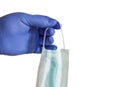 The hand of a purple rubber glove holds a medical face mask against viruses and bacteria, isolated by clipping on a Royalty Free Stock Photo