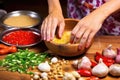 hand pushing cloves of fermented garlic into a bowl of vegetables