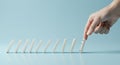 Hand Pushing Domino Causing a Chain Reaction on Blue Surface Royalty Free Stock Photo