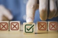 Hand pushing green correct sign symbol in front of Red Cross sign on wooden block cube for business proposal and document approve