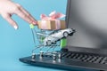 Hand pushing shopping cart with car on laptop keyboard on blue background. Online shopping vehicles on the Internet Royalty Free Stock Photo