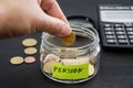 Hand put coins in a glass jar on a background of a calculator. . Adding money to your pension bank concept. Concept of saving mone Royalty Free Stock Photo