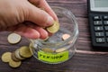 Hand put coins in a glass jar on a background of a calculator. . Adding money to your pension bank concept. Concept of saving mone Royalty Free Stock Photo