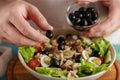 Hand put olive into the bowl with fresh vegetables and canned tuna. Royalty Free Stock Photo