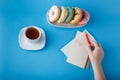 Hand put pen on painting heart with tea and donuts Royalty Free Stock Photo