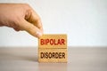 Hand puts blocks with the words Bipolar Disorder - manic depression. Mood disorder characterized by periods of depression and