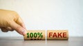 Hand puts blocks with the words 100% fake. Fake news and false information, misleading. Misinformation. Business concept Royalty Free Stock Photo