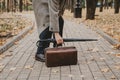 Hand puts brown carpetbag on alley in square