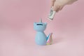 Hand puts a dollar in the moneybox kitten corn blue with a colorful rainbow tail with closed eyes and a unicorn horn on Royalty Free Stock Photo