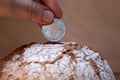 The hand puts the euro coin in the bread like in a money box. Economy, investment in food. food crisis. Agriculture. Agronomy.