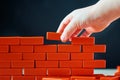 Hand puts last brick on a wall. Concept of construction and building