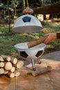 Hand puts piece of wood in round barbecue