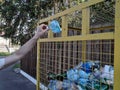 Hand puts a plastic bottle in a recycling bin.