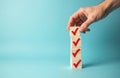 Hand puts red tick on wooden cube stack representing checklist on blue. Task completed box marked with red. Concept for survey or