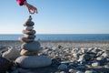 A hand puts a stone on a tower on the beach. Construction of a house by the sea. Background for real estate advertising. Royalty Free Stock Photo