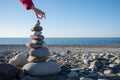 A hand puts a stone on a tower on the beach. Construction of a house by the sea. Background for real estate advertising. Royalty Free Stock Photo