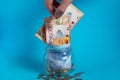 The hand puts a tenge coin in a glass jar with money. Kazakhstan. KZ. KZT. Banknote, paper currency, coins, Bank. Salary, credit, Royalty Free Stock Photo