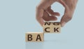 The hand puts wooden cube with the letter from the word back and bang. wooden cubes standing in hand