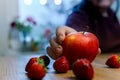 Hand putting an apple on a table with strawberries