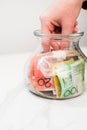 hand putting an Australian dollar banknote in a transparent jar on the white background Royalty Free Stock Photo